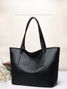 Detail of black woven tote bag made of soft synthetic leather with textured finish