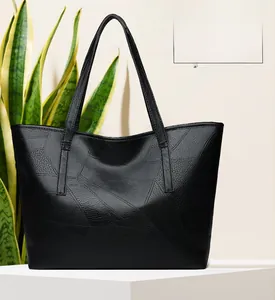 Close-up of black woven geometric textured tote bag with long handles on a minimal stand