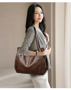 Dark brown leather tote bag with vintage texture shown on a model in a minimalist setting