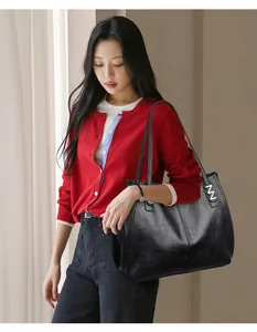 Close-up of black leather tote bag with silver logo detail and long shoulder straps