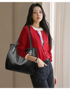 Close-up of black leather tote bag featuring stylish silver Z-shaped metal ornaments