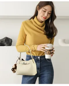 Detail of cream leather bucket bag featuring lychee grain and silver clasp with bear charm