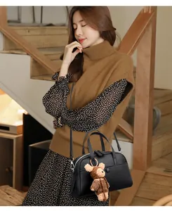 Close-up of black lychee leather Boston bag with cute brown knit bear charm accessory