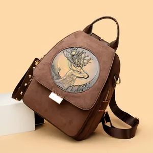 Vintage brown suede backpack featuring an embossed deer head medallion and gold rivets