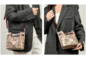 Detalle de bolso cubo con estampado de serpiente, ribete de cuero rojo y cierre de giro plateado