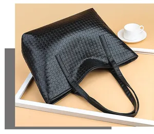 Detailed view of black woven tote bag with Intrecciato texture and slim shoulder straps
