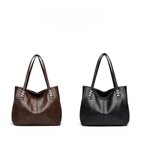 Detail of minimalist leather tote bags in brown and black with silver metallic M hardware
