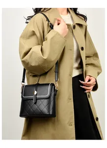 Detail van zwarte gewatteerde leren bucket bag met gouden gesp en schouderband