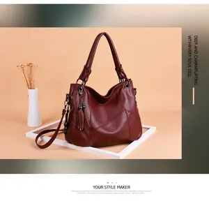 Détail d'un sac cabas en cuir bordeaux avec décoration à glands et coutures texturées