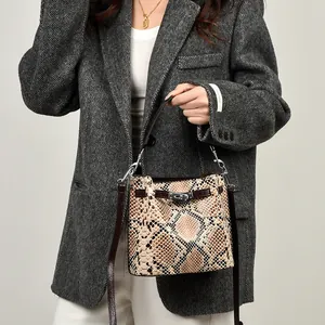 Bolso cubo de cuero con estampado de serpiente, cierre giratorio plateado y correa