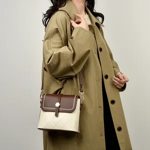 Gewatteerde bucket bag met contrastkleuren en gouden details getoond op een model
