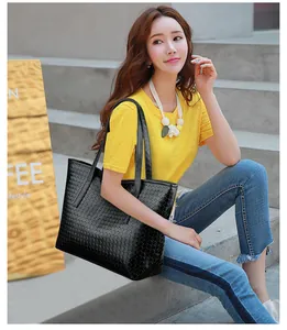 Outdoor shot of a black woven pattern tote bag with long double shoulder straps