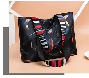 Detail of colorful feather print on black oxford tote bag with striped shoulder strap