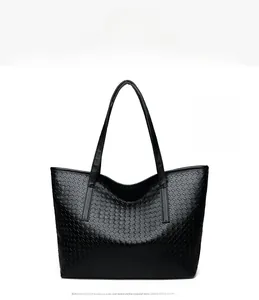 Detailed view of black woven tote bag made of soft faux leather with dual long straps