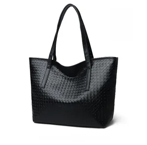 Close-up of the black woven leather texture and wide shoulder strap of this tote bag