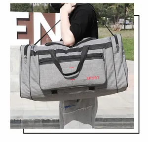 Mannequin portant un grand sac de voyage sport gris avec bandoulière noire à l'extérieur