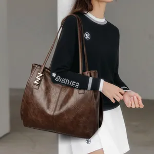 Minimalist dark brown leather tote bag with metallic M ornament for women's workwear
