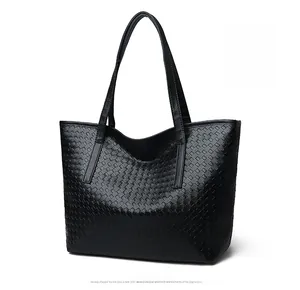 Detailed view of black woven tote bag featuring diamond textures and dual shoulder straps