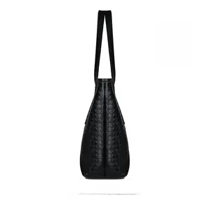 Side view detail of a black woven leather tote bag with dual straps on white background