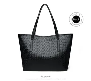 Detail view showing the back side of a black woven tote bag with smooth PU leather straps