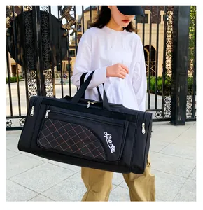 Close-up of black quilted travel bag with orange stitching and white Sports logo print