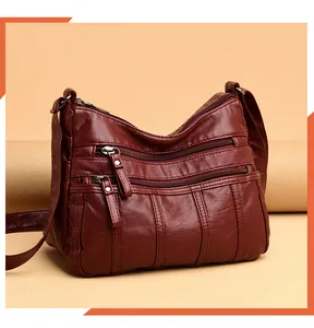 Dettaglio della borsa a tracolla bordeaux in pelle con tasche multiple a zip