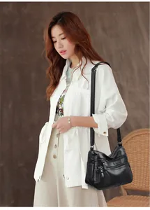 Detail of vintage-style black leather multi-pocket crossbody bag with adjustable strap