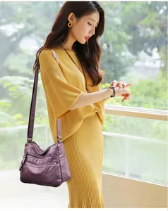 Detail of purple soft leather crossbody bag with multiple zippers worn by model