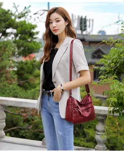 Detail of burgundy washed faux leather crossbody bag with functional multi-zipper pockets
