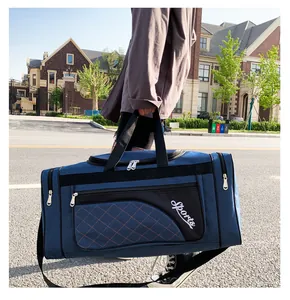 Deep blue quilted sports duffel bag with shoulder strap shown in an urban street setting