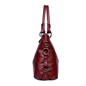 Sac à main en cuir rouge foncé avec ornements en métal et rivets de style industriel