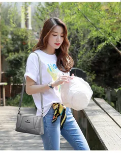 Borsa a tracolla grigia patchwork con logo a canguro in metallo su sentiero esterno