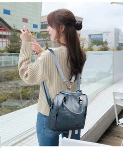 Detail of greyish blue quilted leather backpack with gold kangaroo logo and zippers