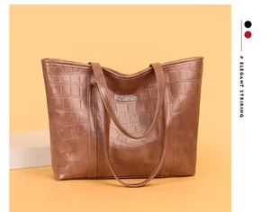 Close-up of brown crocodile embossed texture and silver metal logo on large tote bag