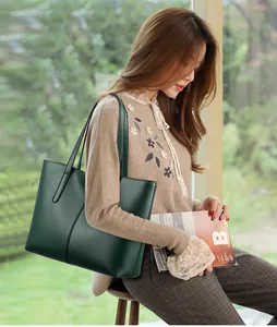 Detalle de bolso tote de cuero verde oscuro llevado por modelo en un ambiente de oficina