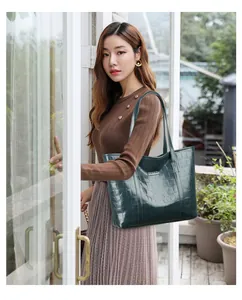 Close-up of dark green faux crocodile leather tote bag with metallic logo detail