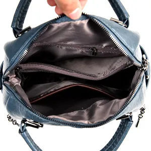 Interior view of navy blue leather backpack with multi-compartment lining and metal zippers