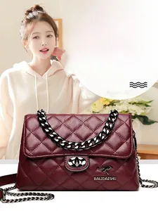 Macro detail of wine red quilted leather bag with metallic kangaroo twist-lock and chain