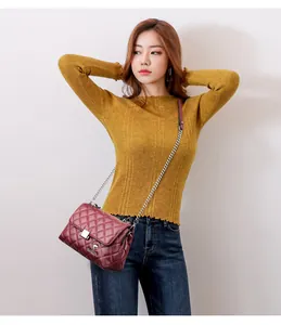 Detail of burgundy quilted leather crossbody bag with metal twist lock and chain strap