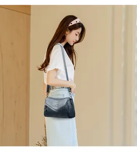 Détail du sac seau en cuir bleu foncé montrant le logo en métal et les coutures