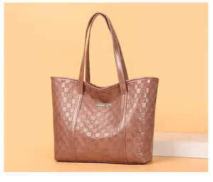 Gros plan sur un cabas matelassé marron avec logo en métal et texture à losanges