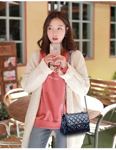 Close-up of quilted navy leather bag with silver chain strap worn by a model