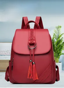 Detail of red-brown pebble leather backpack with decorative tassel and metal ring