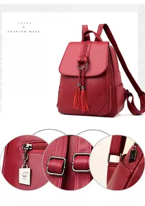 Detail of red pebbled leather backpack showing fringe tassels and polished metal hardware