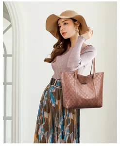 Détail du sac cabas marron à motif damier gaufré avec une plaque logo métallique