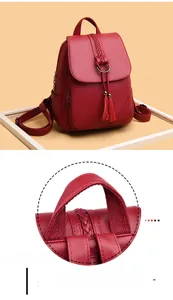 Close-up of pebble leather texture with tassel and woven handle stitching on red backpack