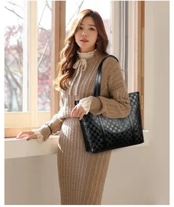 Détail d'un sac cabas noir matelassé avec texture à damier et poignées en cuir