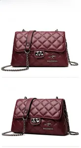 Detail of wine red quilted crossbody bag featuring a golden lock and chain strap