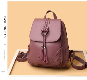 Close-up of pink leather backpack featuring tassel pendant and woven handle detail