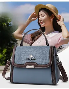 Detail of blue faux crocodile texture and kangaroo metal logo on a stylish shoulder bag